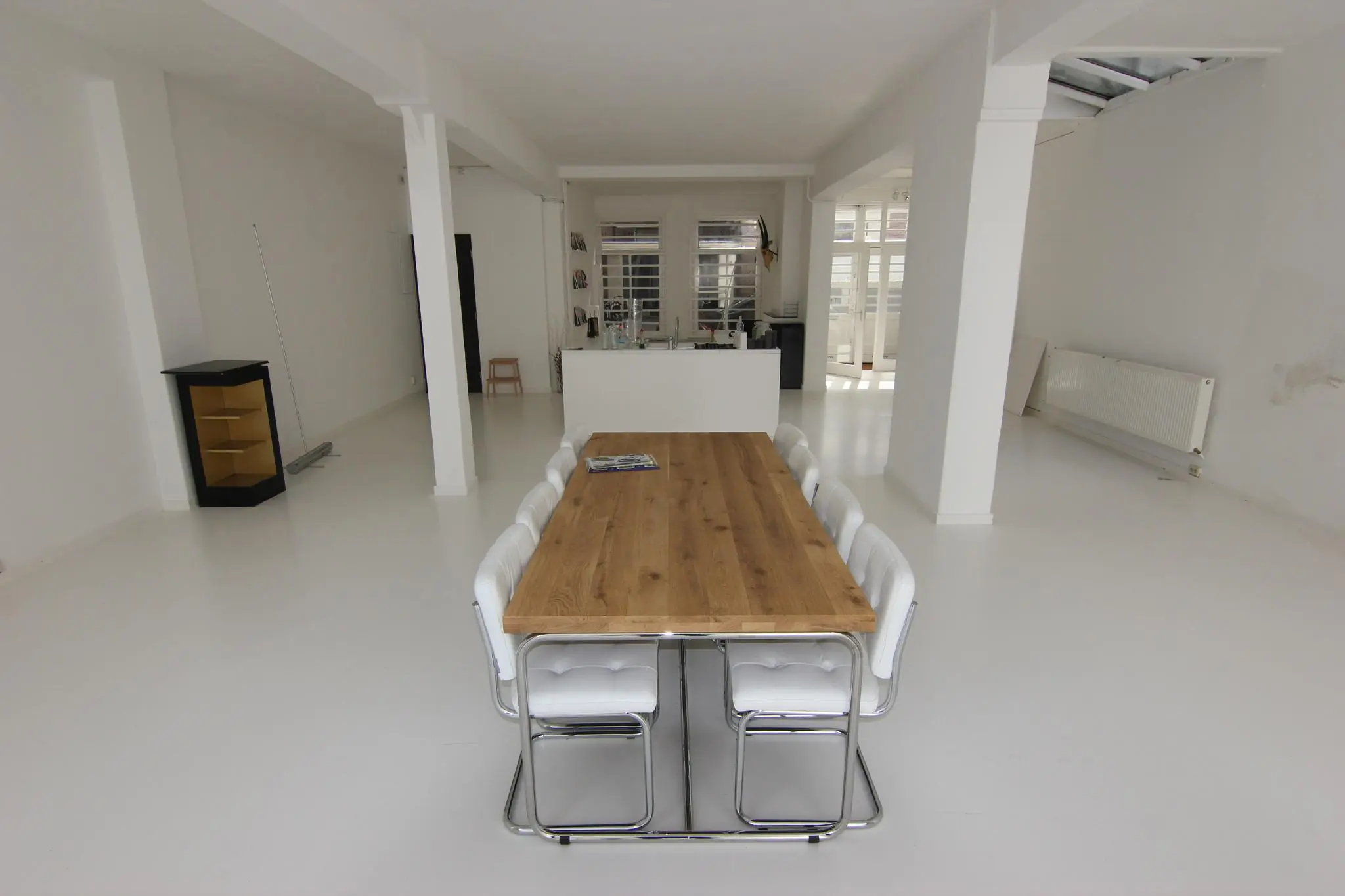 Lichte, minimalistische eetkamer aan de Graaf Florisstraat met een lange houten tafel en witte stoelen.